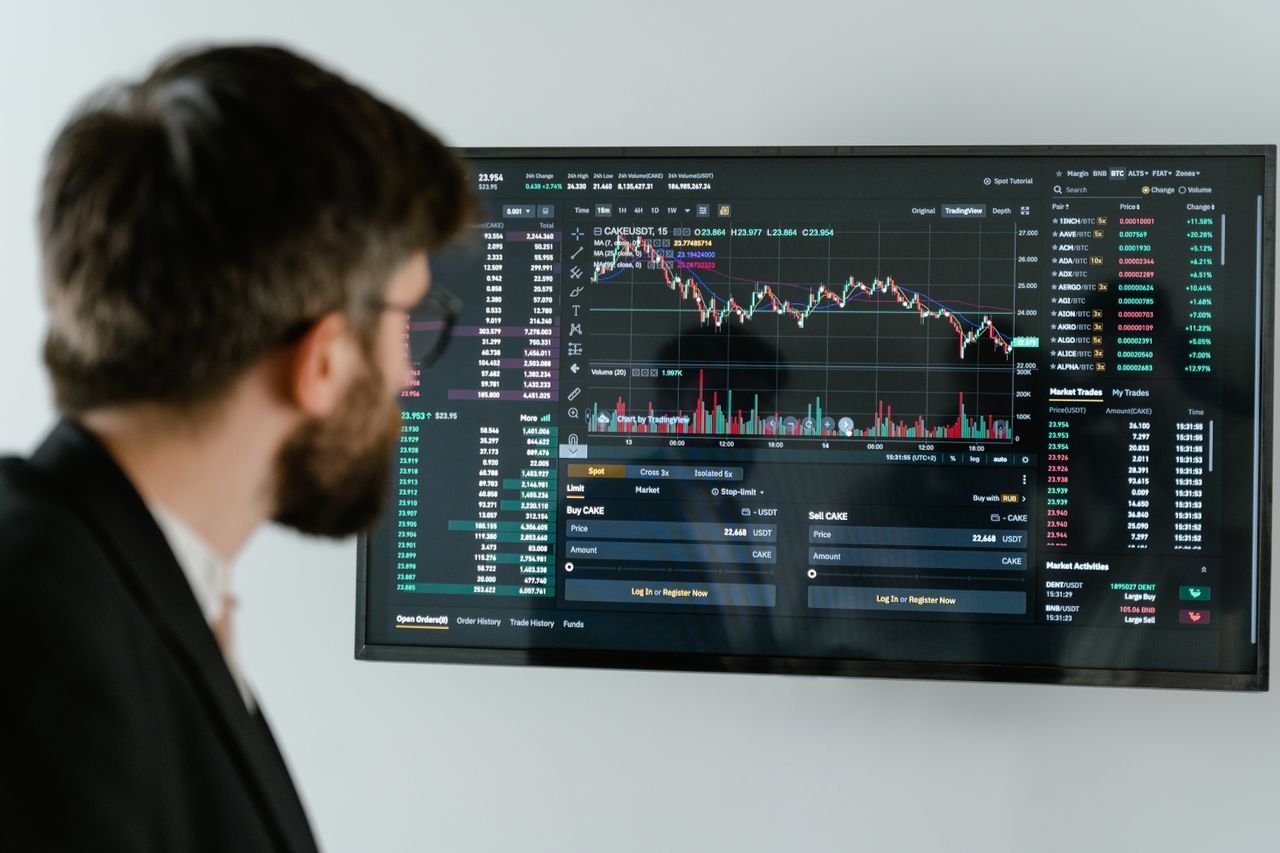 A businessman in a suit looks at a screen displaying stock market charts and data analysis.